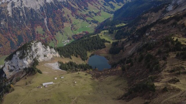 Kleiner dunkler Bergsee im Talkessel mit Felsschutt und Herbstwald &ndash; Luftaufnahme aus den Alpen