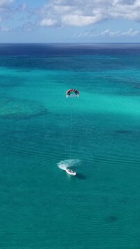 Parasail In Providenciales Overseas Territory Turks And Caicos Islands. Tourists Parasailing Over A Tropical Ocean On A Sunny Day. Landmark Coast. Tropical Skyline. Providenciales Overseas Territory.