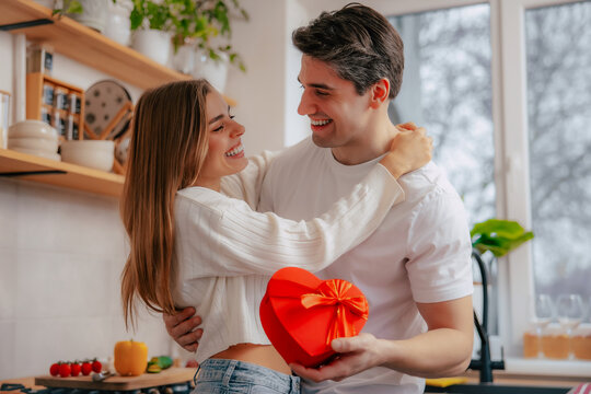 Smiling couple sharing affectionate look with heart-shaped gift