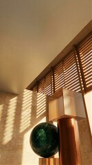 Fototapeta premium Modern corporate lobby interior with sculptural green stone sphere and geometric copper column beneath wooden blinds. Architectural design, luxury office, warm natural lighting