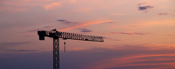 construction crane silhouette against colorful sunset sky © Anna