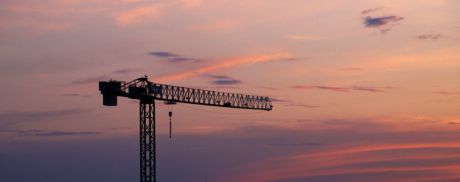 construction crane silhouette against colorful sunset sky