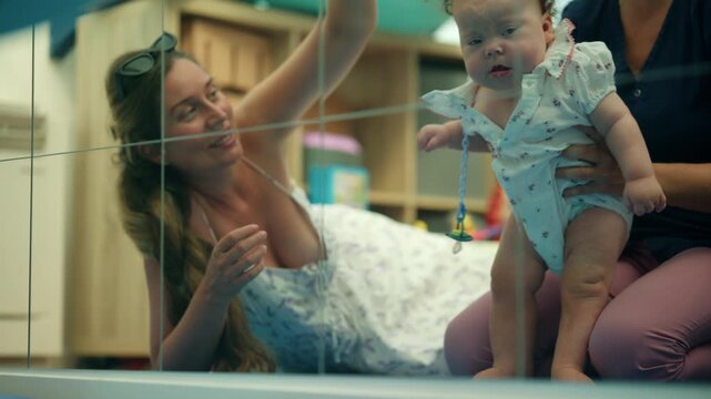 Baby observing a toy, engaging in play and early learning activities with parents or caregivers in a development center