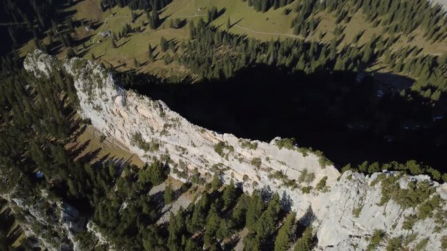 Dunkler Bergsee im grasbewachsenen Kar mit hellem Ger&ouml;ll und Schneefeld &ndash; Luftaufnahme