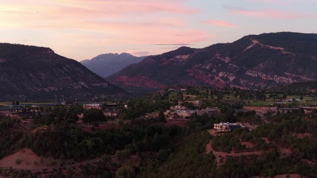 Aerial of mountain valley landscape in Durango Colorado at dusk with colorful sunset and residential development nestled among rugged mountain ranges