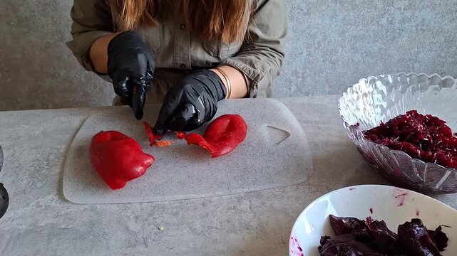 Preparing red peppers for cooking in a kitchen setting with a person wearing black gloves