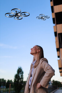 Young businesswoman looks at sky filled with drones