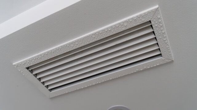 White HVAC Air Vent Grille with Condensation Droplets on Wall