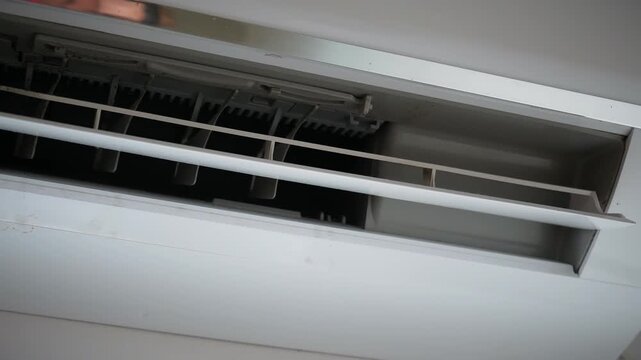 Air conditioner vent and dusty cooling unit.
A close-up view shows the open outlet and adjustable louvers of a wall-mounted split air conditioner with visible dust.