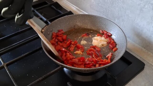 Cooking with red peppers in kitchen on a stovetop
