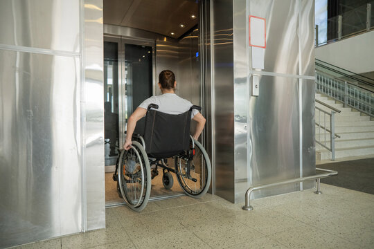 A Caucasian woman in a wheelchair uses an elevator.