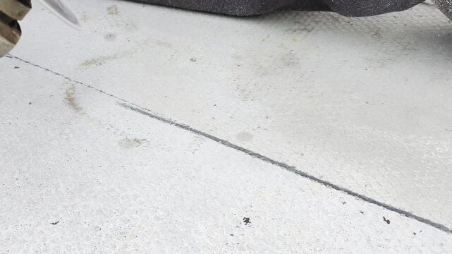 Angle grinder cuts concrete floor creating cloud of dust particles. Fine dust particles fly around as power tool cuts straight line during renovation works in industrial room close up