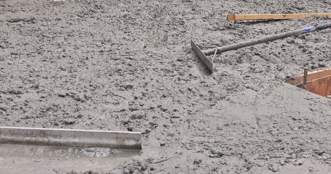 Workers mix spread wet concrete slab to create strong foundation at construction site