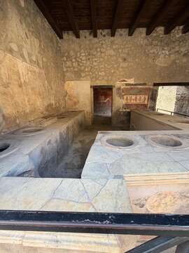 Ancient Roman thermopolium counter with food jars and fresco, Pompeii, Italy