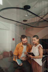 Creative business professionals collaborating on digital tablet, discussing startup project in...