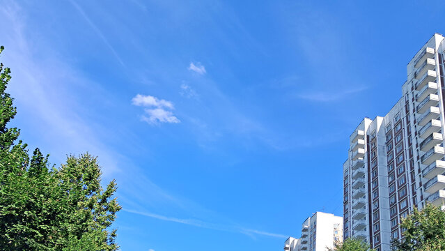 High-rise residential towers with blue sky and greenery