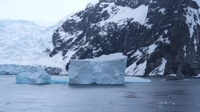 Antarctica Dramatic Landscape with Large Icebergs Floating, Epic Mountains Covered in Snow. Moody Weather. Beautiful Remote Nature Destination