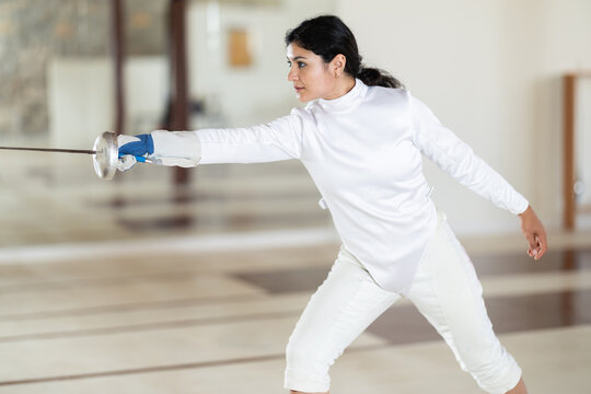 Argentine woman in a fencing class, she is in a white uniform with a sword in her hands, practicing movements