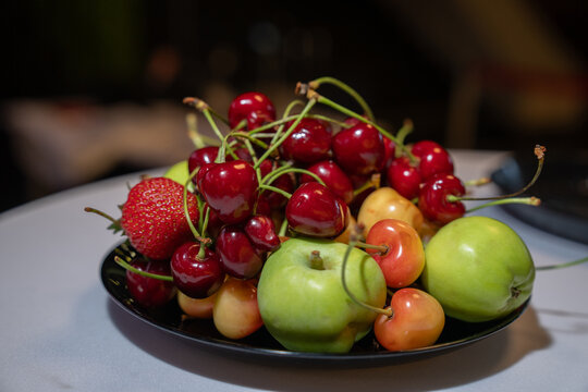 Red cherries - ripe, dark burgundy and bright red with green stems - form the basis of the composition.