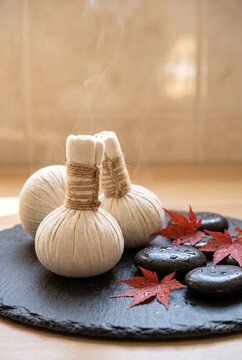 Two traditional steamed herbal poultice bags (luk pra kob) tied with natural twine