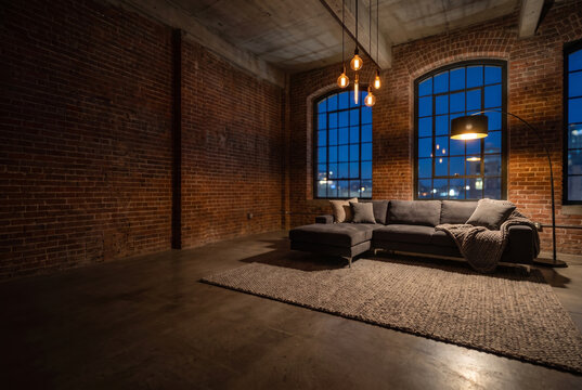 Sunless, nocturnal loft living room with raw exposed red brick walls and high concrete ceilings