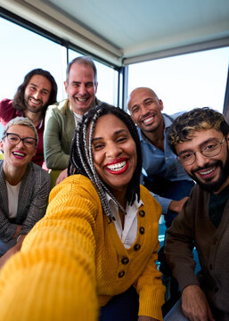 Vertical Selfie of a group of happy multiracial business people taking photo with a phone in the office