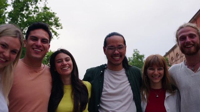 Multiracial group of young students embracing and laughing together on a city street, enjoying their time together and expressing genuine happiness and friendship