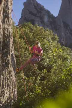 Young hispanic woman rappelling rock face on climbing day