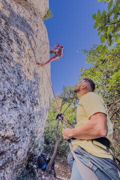 Young woman rock climbing while partner belaying