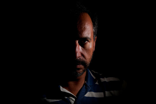 dark-haired, white European man with a trimmed beard, of mysterious appearance and light.