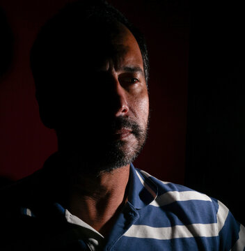 dark-haired, white European man with a trimmed beard, of mysterious appearance and light.