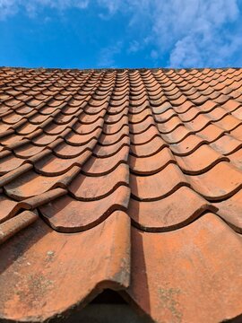 Old clay roof tiles creating a pattern against a clear blue sky