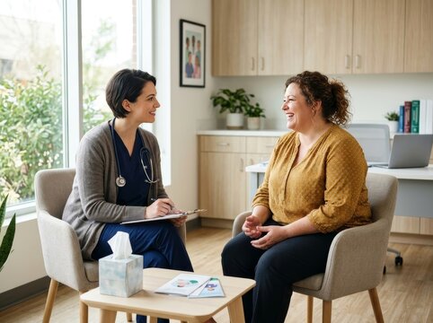 Female doctor talking to smiling woman patient in medical office. Professional healthcare consultation and support session. Friendly communication during checkup in clinic interior.