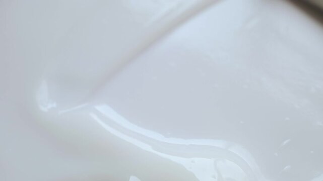 Smooth, creamy white cosmetic product texture being mixed with spatula in macro shot