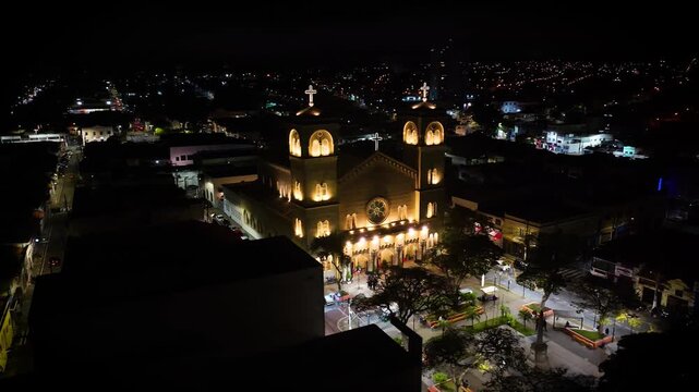 4K aerial night view of an illuminated historic Catholic church in downtown Mogi das Cruzes, S&atilde;o Paulo, Brazil, surrounded by city lights.