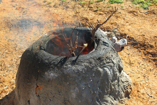 Traditional clay oven tabouna heated with olive tree branches and burning wood fire for bread making