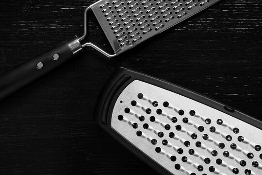 Kitchen utensils and cooking preparation, two metal graters on a dark wooden background, food preparation tools
