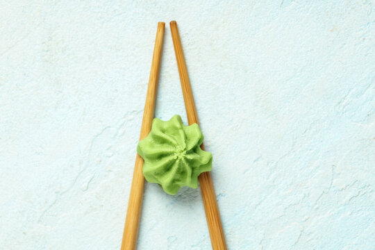 Chopsticks with wasabi paste on light blue background