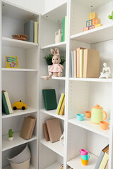 Naklejka premium White bookshelf with toys in childrens room
