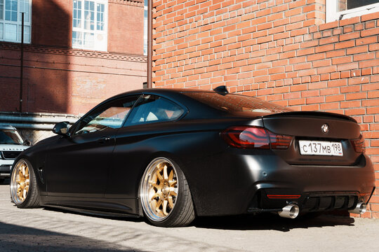Low angle side profile view of a tuned matte black BMW 4 Series F32 coupe car with custom gold SSR alloy wheels and extreme stance lowered suspension. Wrapping car on matte PPF film. 