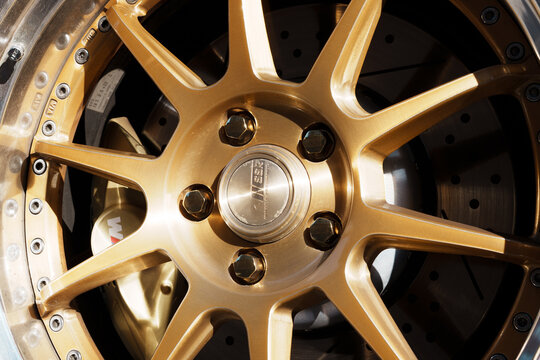 Macro close up of a luxury custom gold alloy wheel rim and tire with a BMW M brake caliper, drilled brake disc rotor. Macro close up of a custom gold SSR alloy wheel rim center cap with bolts. 