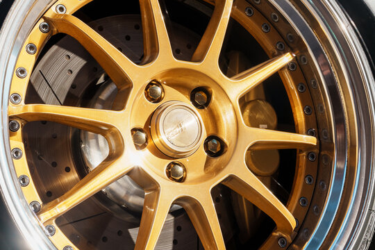 Macro close up of a luxury custom gold alloy wheel rim and tire with a BMW M brake caliper, drilled brake disc rotor. Macro close up of a custom gold SSR alloy wheel rim center cap with bolts. 