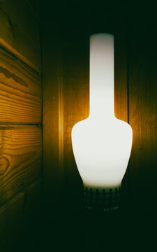 Glowing frosted glass vintage lamp standing near wooden log wall