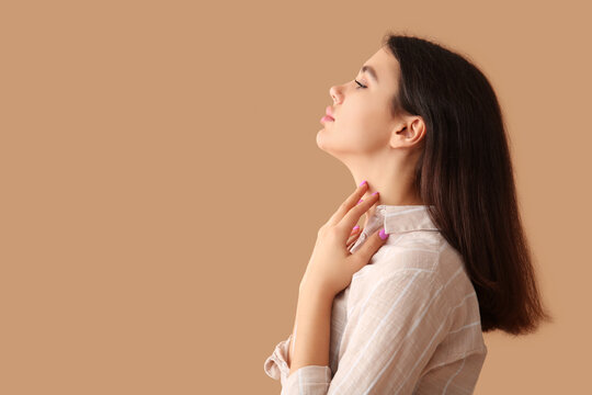 Young woman with thyroid gland problem on beige background
