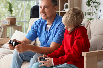 Mature doctor and his little son with game pad talking by mobile phone at home © Pixel-Shot