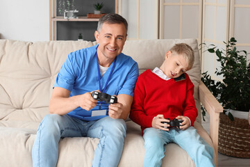 Mature doctor and his little son with game pad talking by mobile phone at home © Pixel-Shot