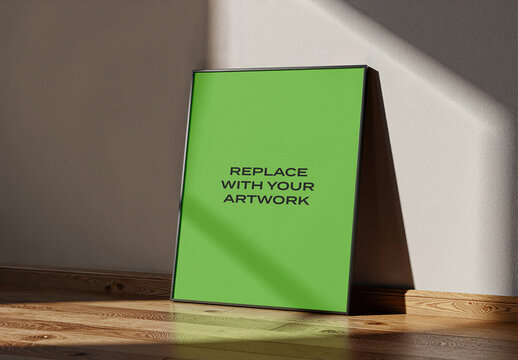Vertical framed poster mockup leaning against an interior wall on a wooden floor, realistic indoor display with natural light and shadow, graphic design presentation, art template