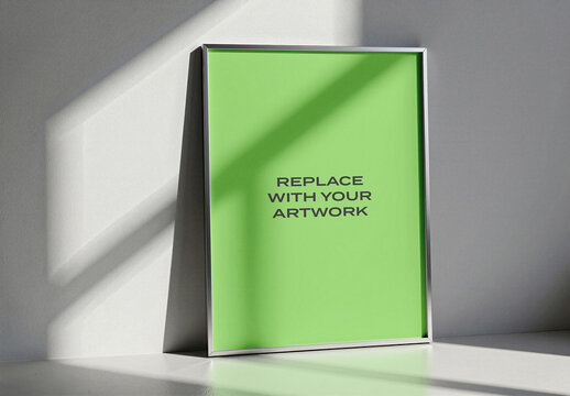 Vertical framed poster mockup with placeholder screen displayed on a white surface against textured wall, natural light casting diagonal shadows, Template