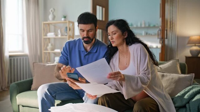 Pregnant wife husband managing home budget sofa. Man showing smartphone