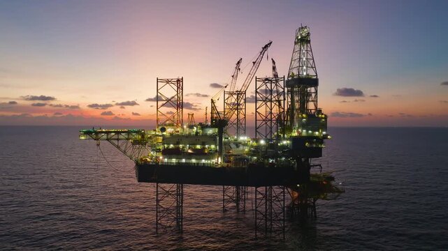 Aerial top view of offshore jack up rig and offshore platform during sunset for oil and gas exploration and production. 